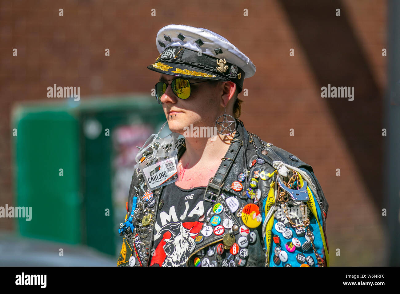 Punk Rocker wearing a leather jacket covered in badges Blackpool, Lancashire, UK. Aug, 2019. Rebellion Festival world's largest punk festival in Blackpool. At the beginning of August, Blackpool's Winter Gardens plays host to a massive line up of punk bands for the 21st edition of Rebellion Festival attracting thousands of tourists to the resort. Over 4 days every August in Blackpool, the very best in Punk gather for this social event of the year with 4 days of music across 6 stages with masses of bands. Stock Photo