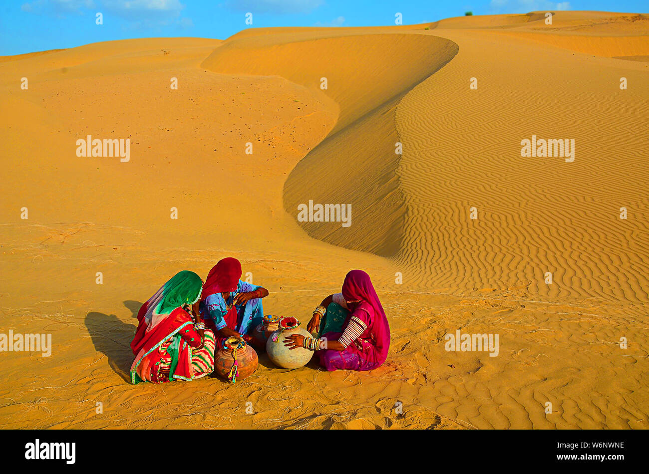 Indian village women sitting on in desert wearing ethnic traditional outfits with water jugs water crises, jaisalmer, rajasthan, india Stock Photo