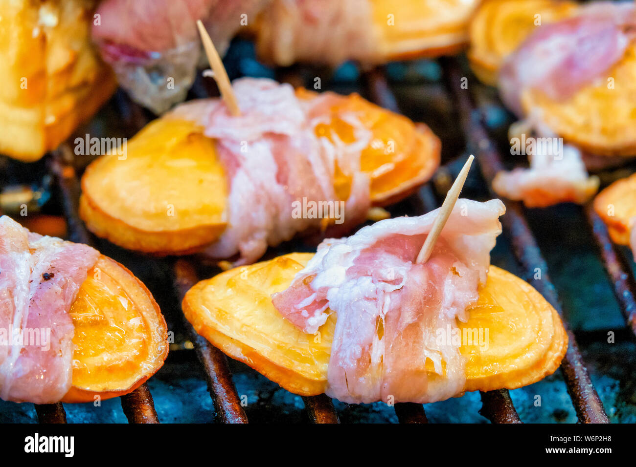 Oscypek, a traditional polish smoked cheese, with bacon on a grill. Stock Photo