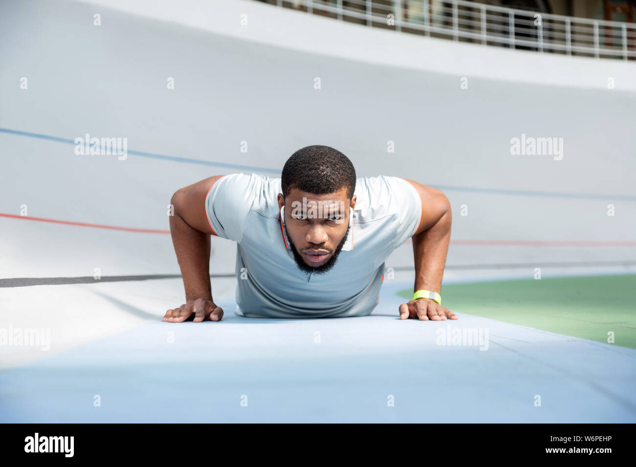Determined athletic man doing push-ups at the stadium Stock Photo