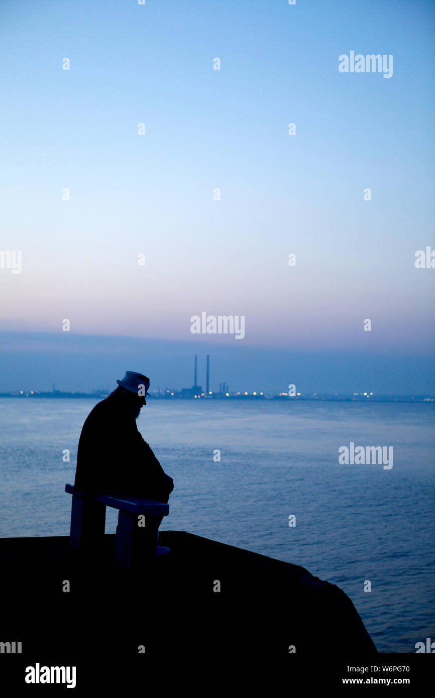 Old man sitting on bench by the sea Stock Photo