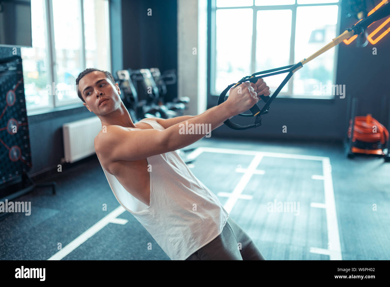 Good looking nice man using trx straps for workout Stock Photo