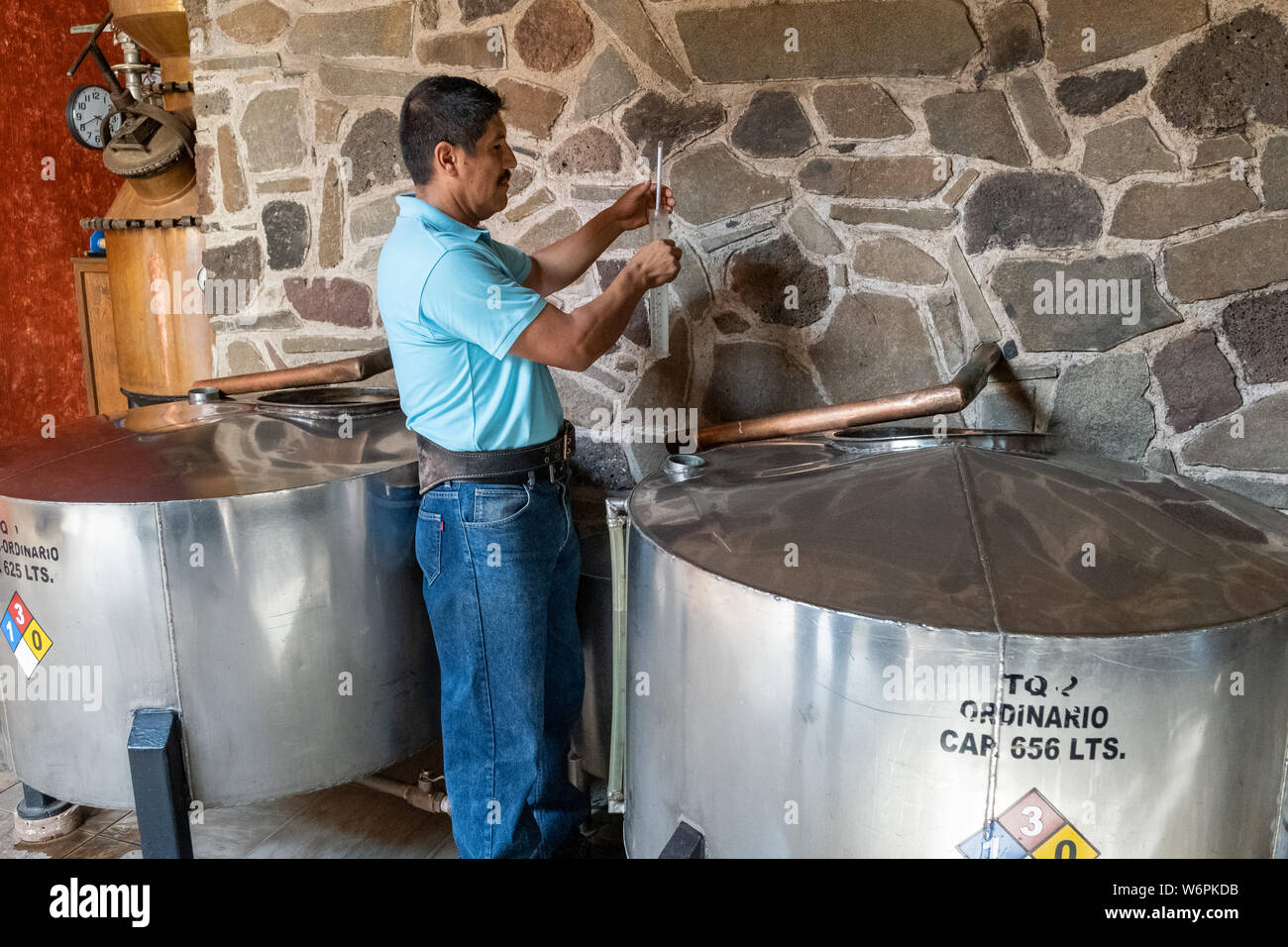 A worker checks the gravity of fresh tequila from the still before it is put in barrels for