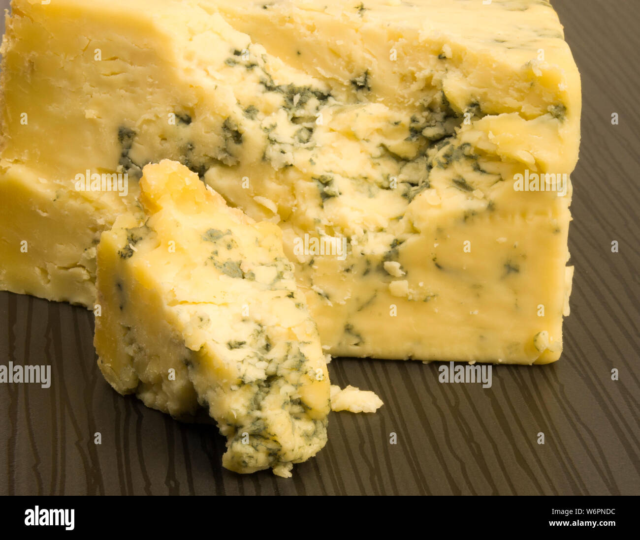 Crumbling blue cheese on a tiled table. Stock Photo