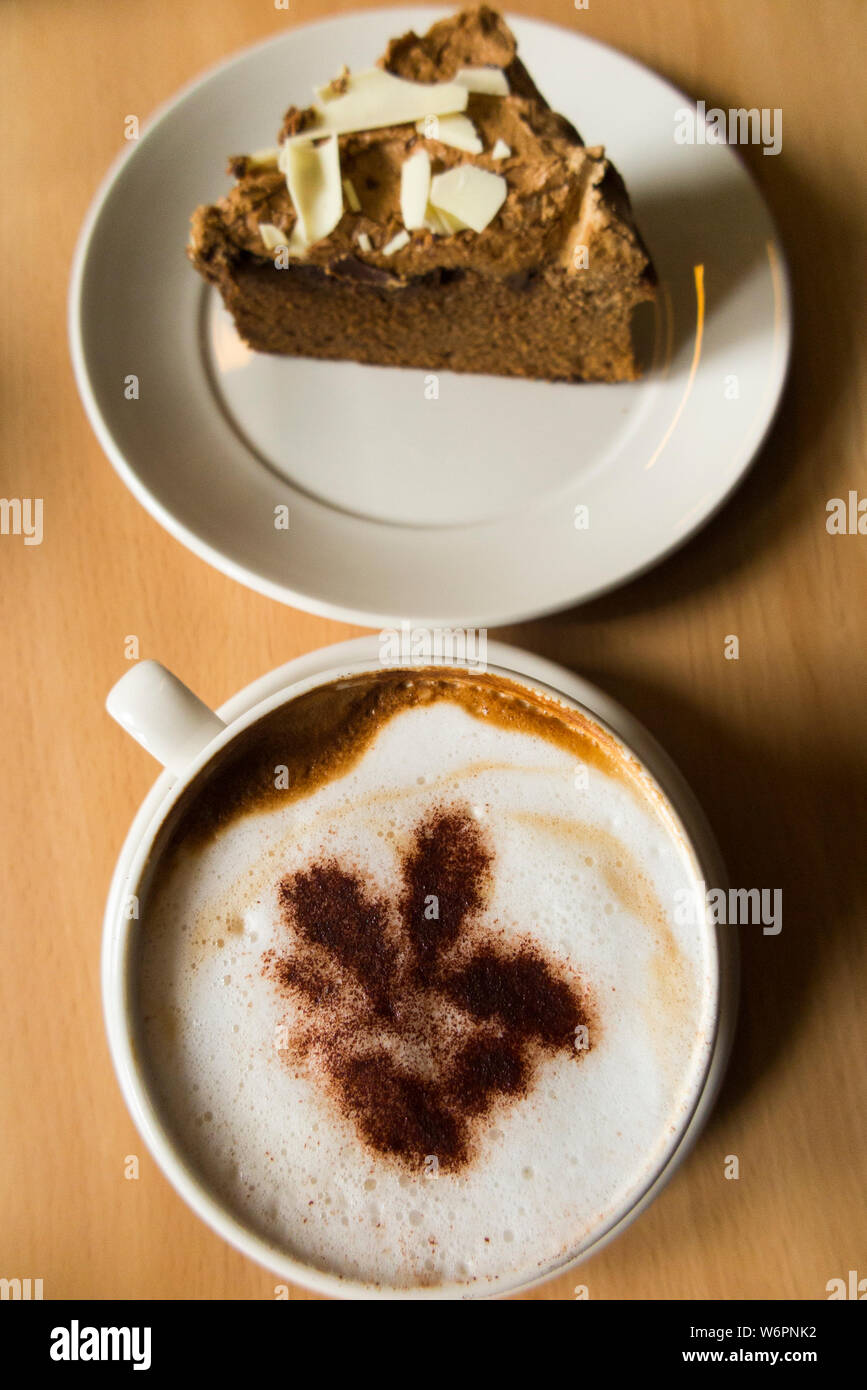 Coffee and cake in a National Trust cafe at a stately home / house. The the cappuccino coffee has the National Trust Oakleaf trademark logo in sprinkled chocolate. UK (110) Stock Photo