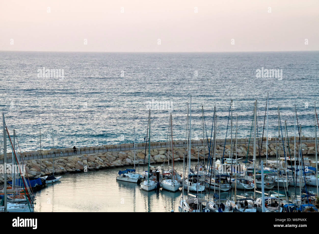 Boats are docked at the Mediterranean Sea near the Herod's Hotel in Tel Aviv at sunset in winter. Stock Photo