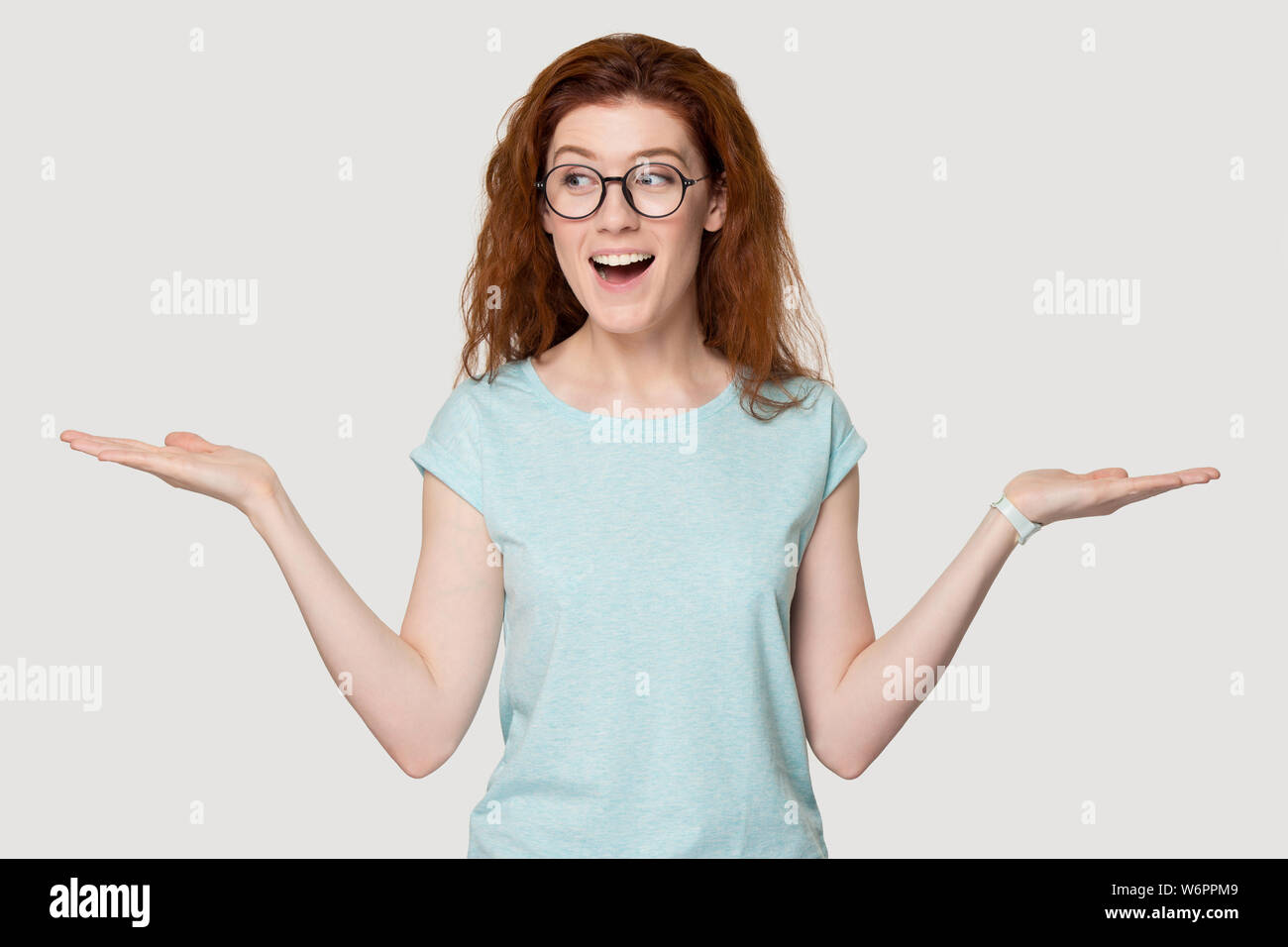 Redhead funny woman in glasses stretched hands makes choice Stock Photo