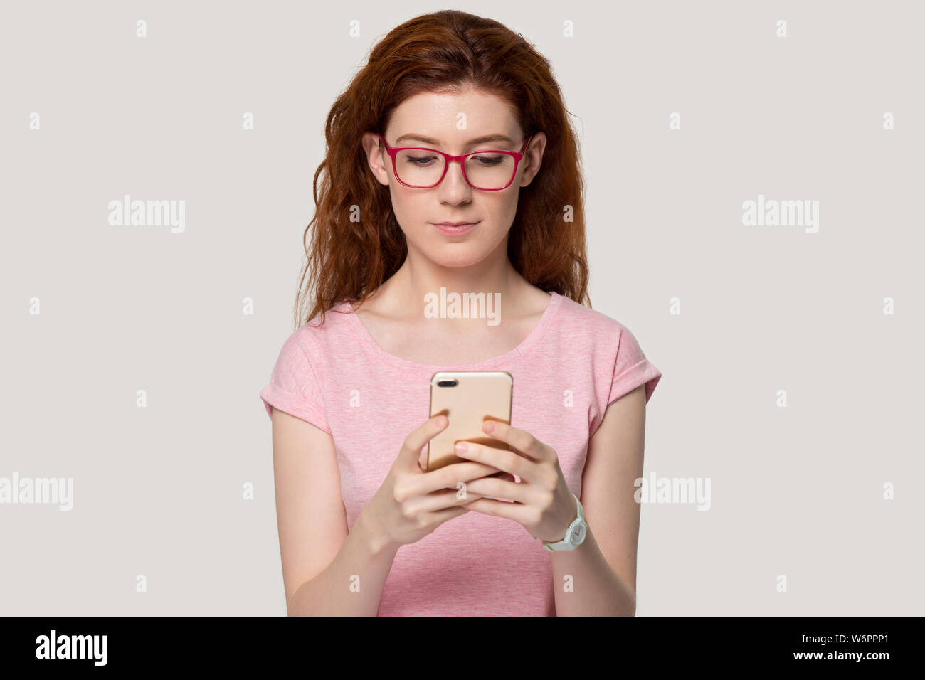 Pretty redhead woman looking at mobile phone screen studio shot Stock Photo