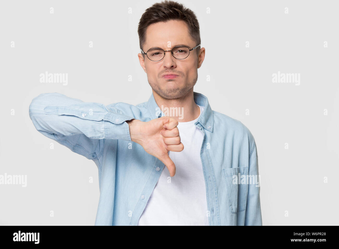 Man looking at camera showing thumbs down negative feedback gesture Stock Photo
