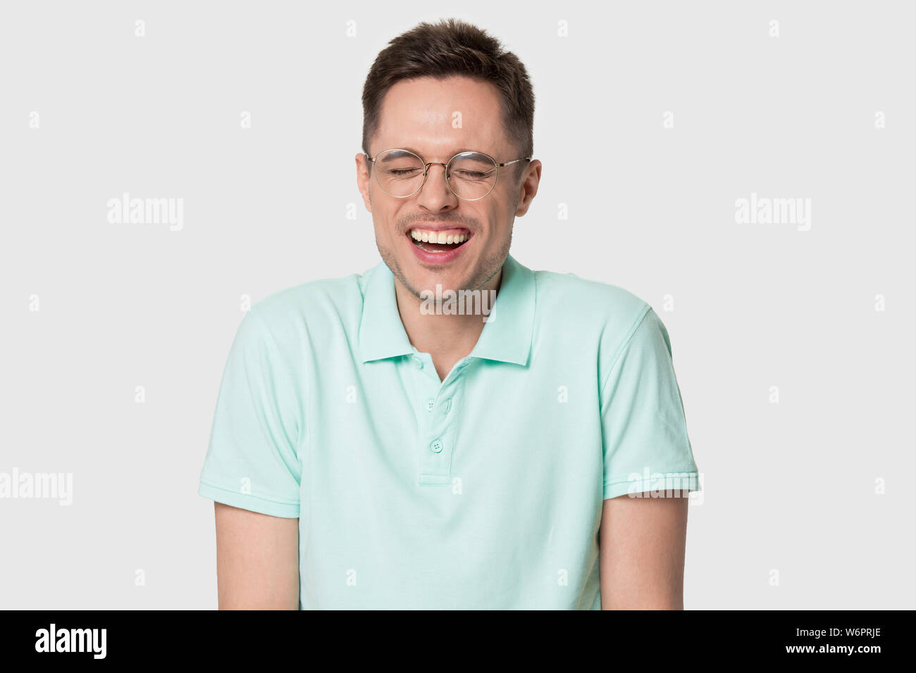 Headshot portrait funny man in glasses laughing on grey background