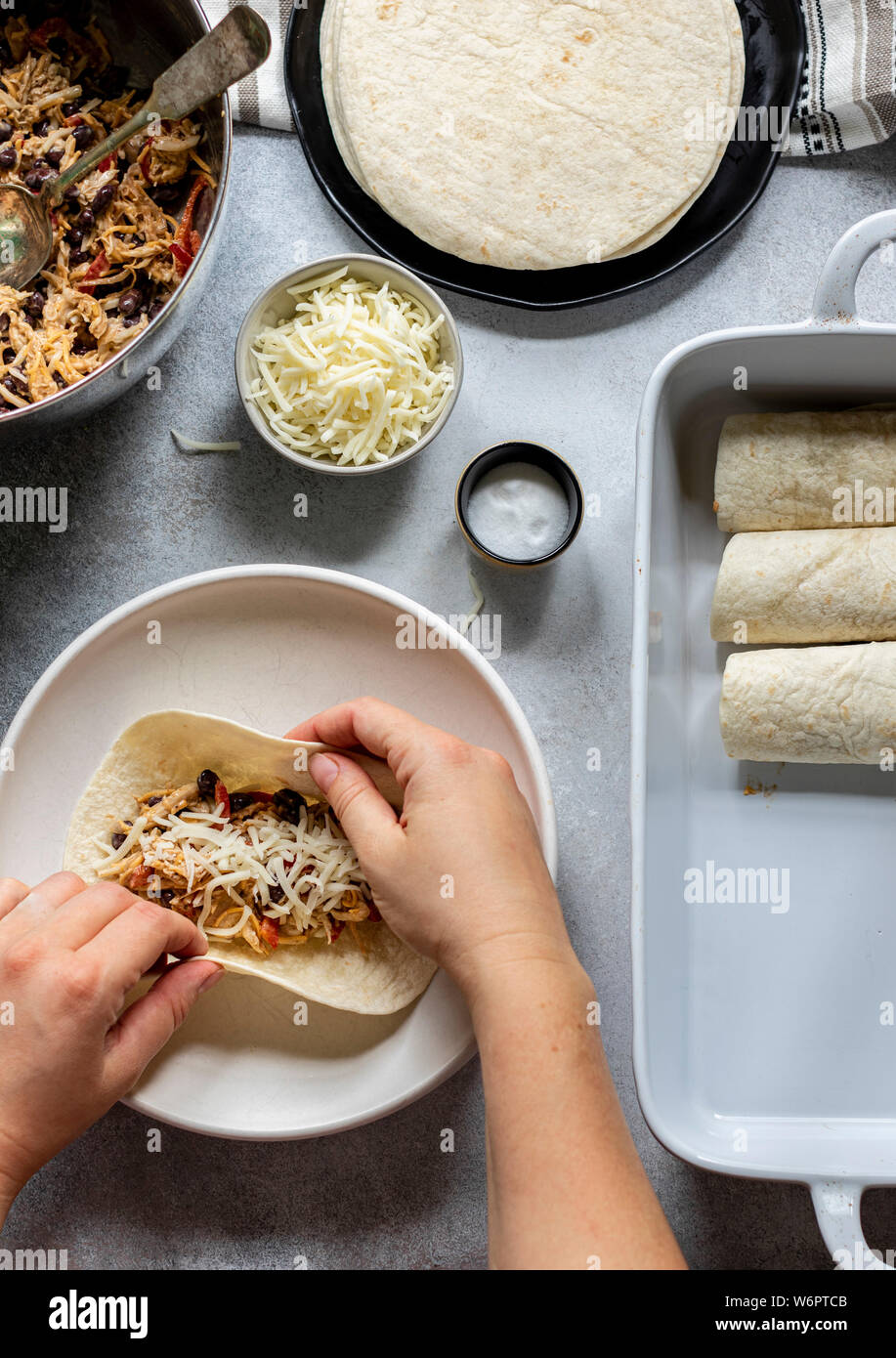 Enchiladas in the making. Tortillas on the plate filled with cheesy