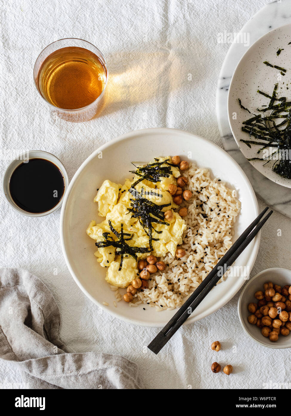 Japanese style scrambled eggs with rice chickpeas and nori served in white bowl with chopsticks Stock Photo