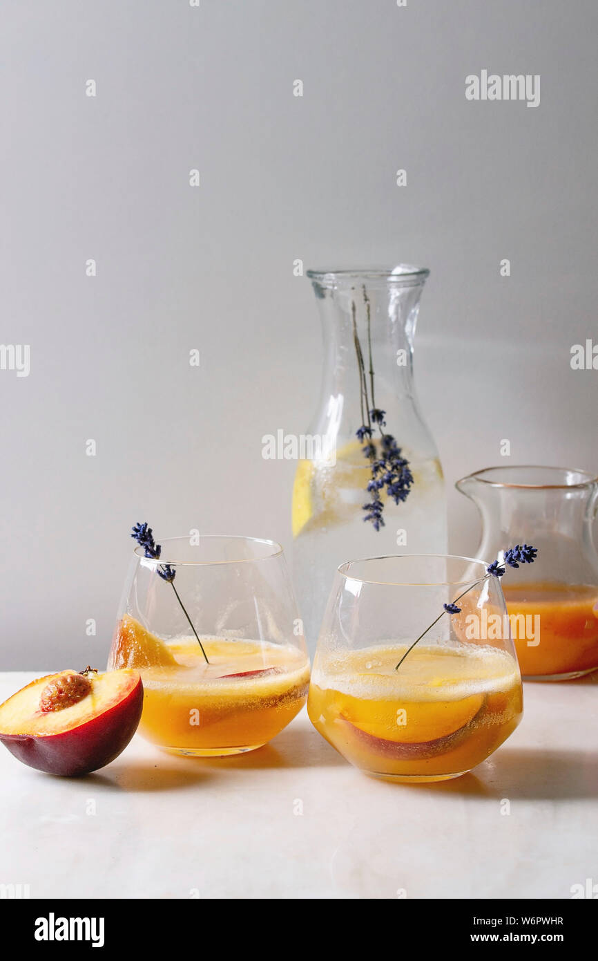 https://c8.alamy.com/comp/W6PWHR/peach-cold-lemonade-or-bellini-cocktail-with-lavender-flowers-served-in-two-glasses-with-pitcher-of-pesh-juice-and-lemon-soda-water-on-white-marble-ta-W6PWHR.jpg