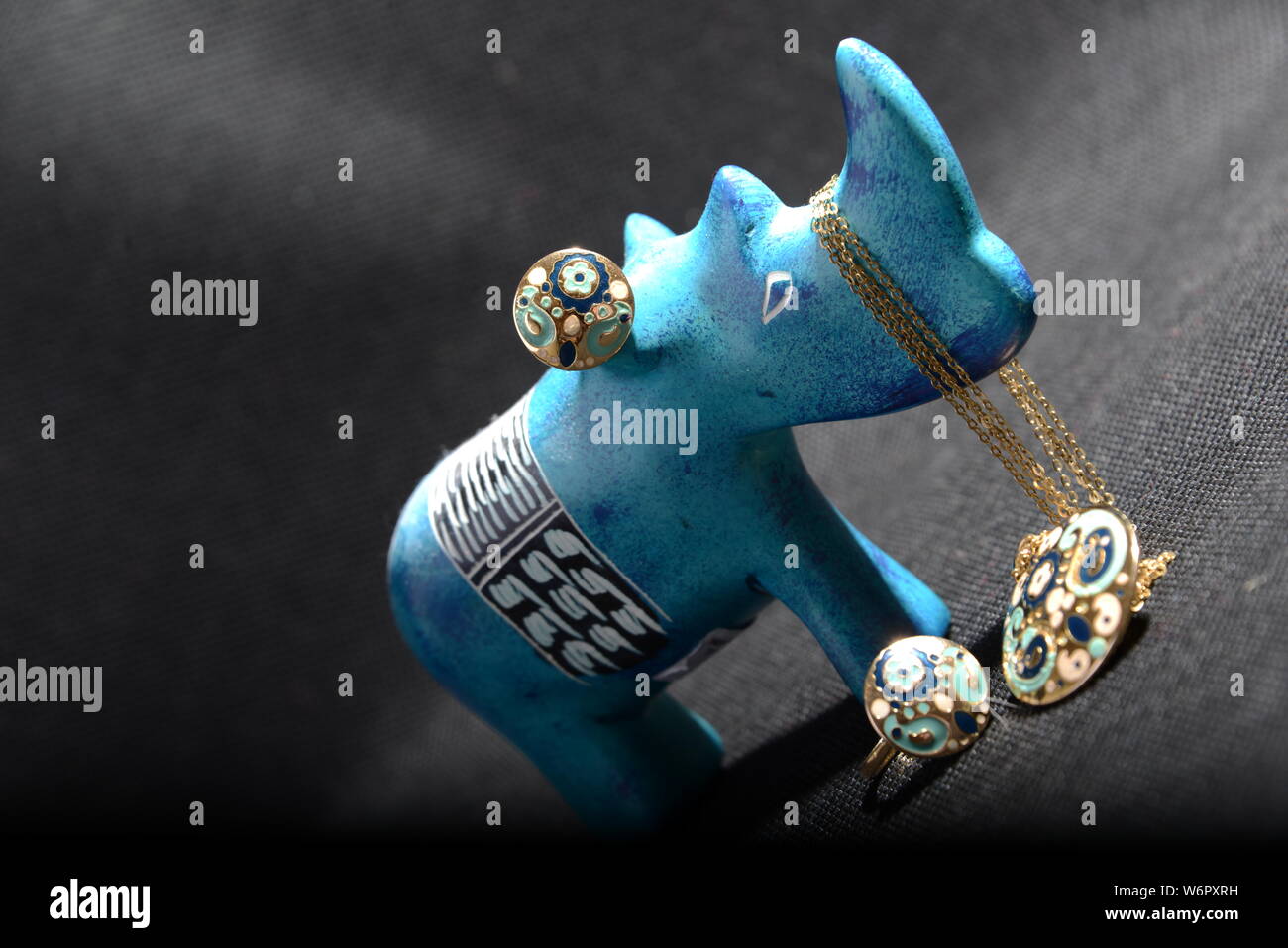 jewellery on the  little blue rhino statue hold the jewellery holder blue necklace gold rings blue and gold rings with Gray background pretty animal Stock Photo