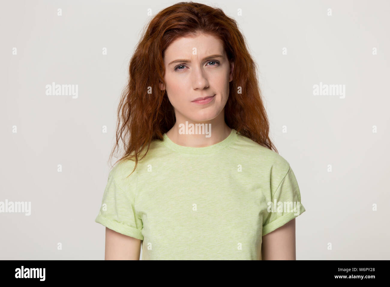 Redhead woman feels confused suspicious pose over grey studio background Stock Photo