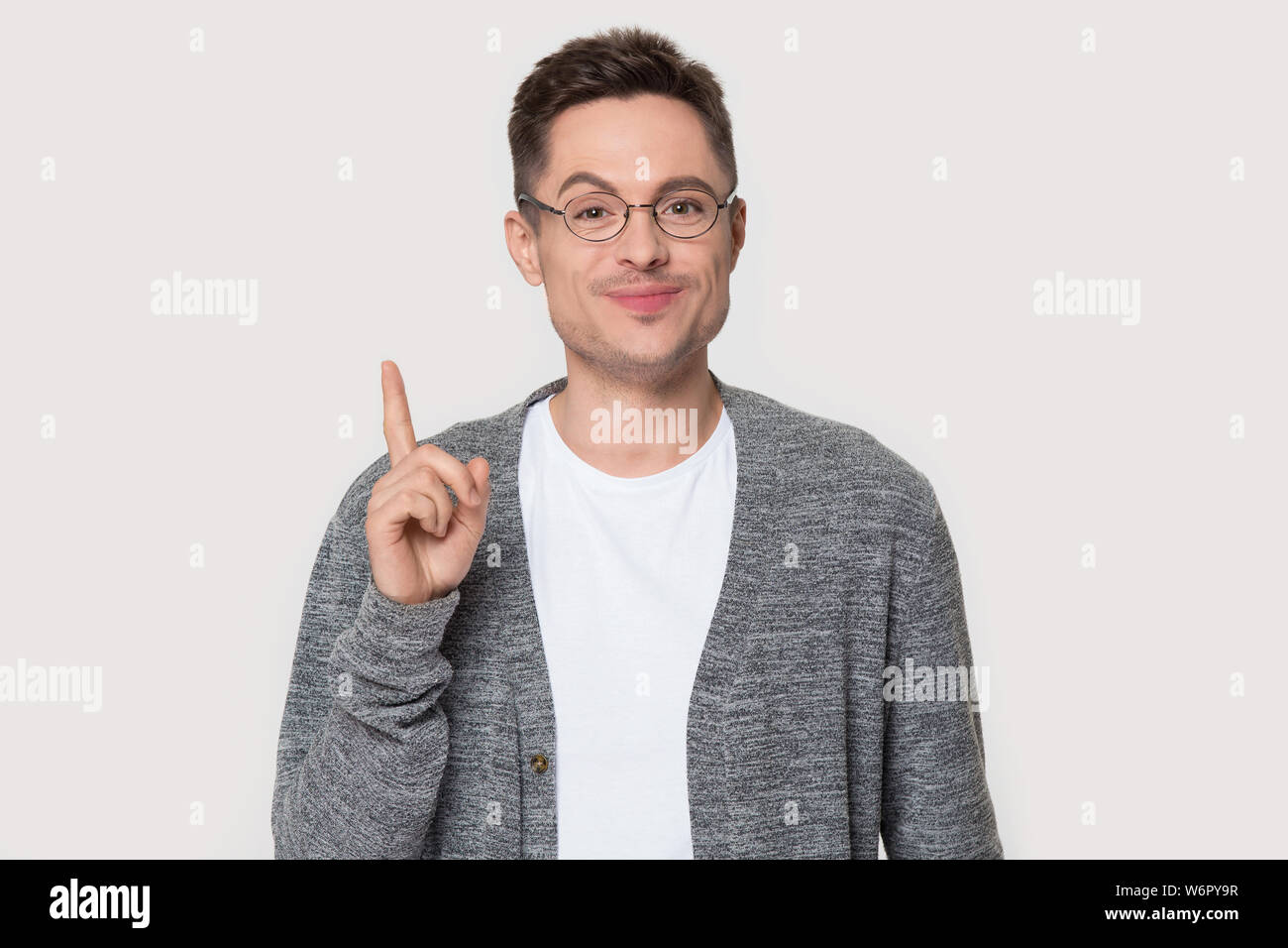 Man raise finger up invent idea pose on grey wall Stock Photo