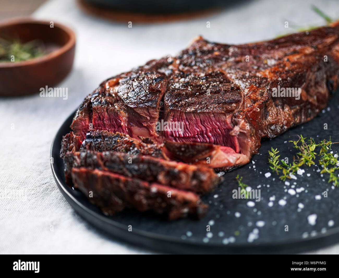 Sliced medium rare grilled angus beef tomahawk steak on a dark plate Stock Photo