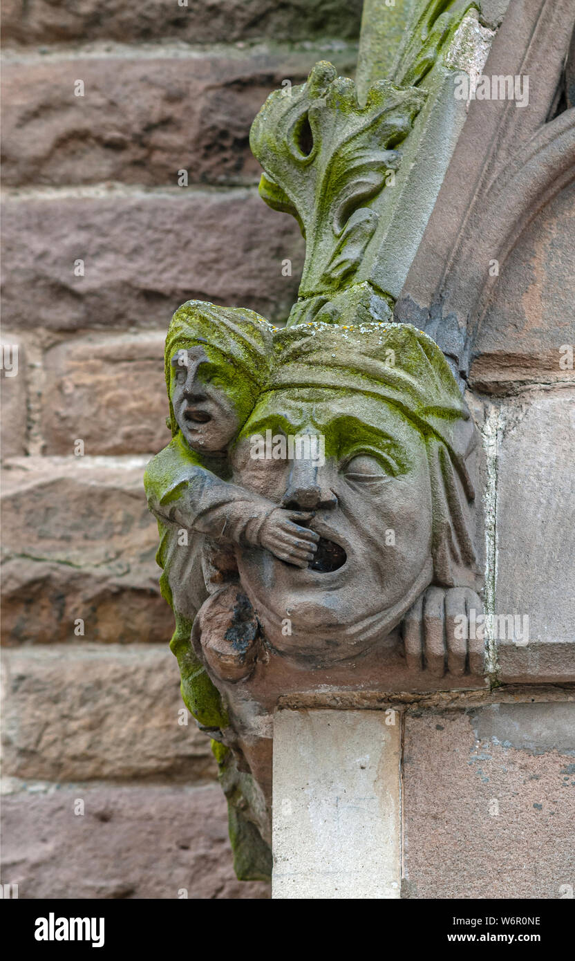 Architectural detail of St.Martin Church in Birmingham, England. It shows a man covering the mouth of a large face. Stock Photo