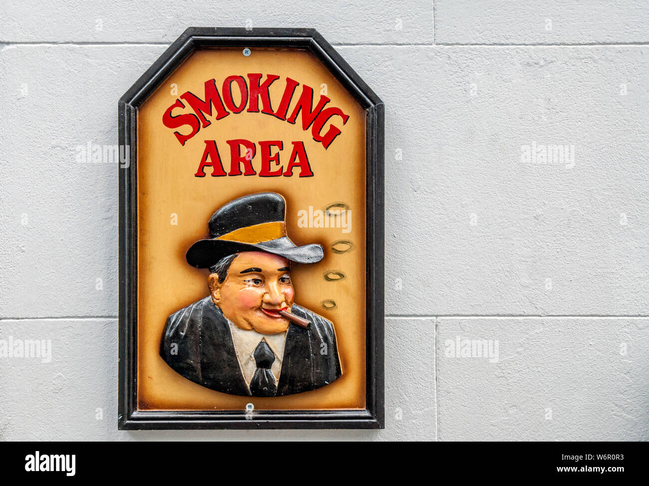 Wooden smoking area sign on a white wall outside of a english pub Stock Photo