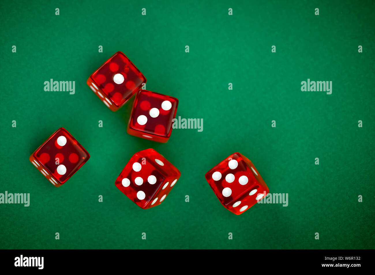 five rolling red dices on green background Stock Photo