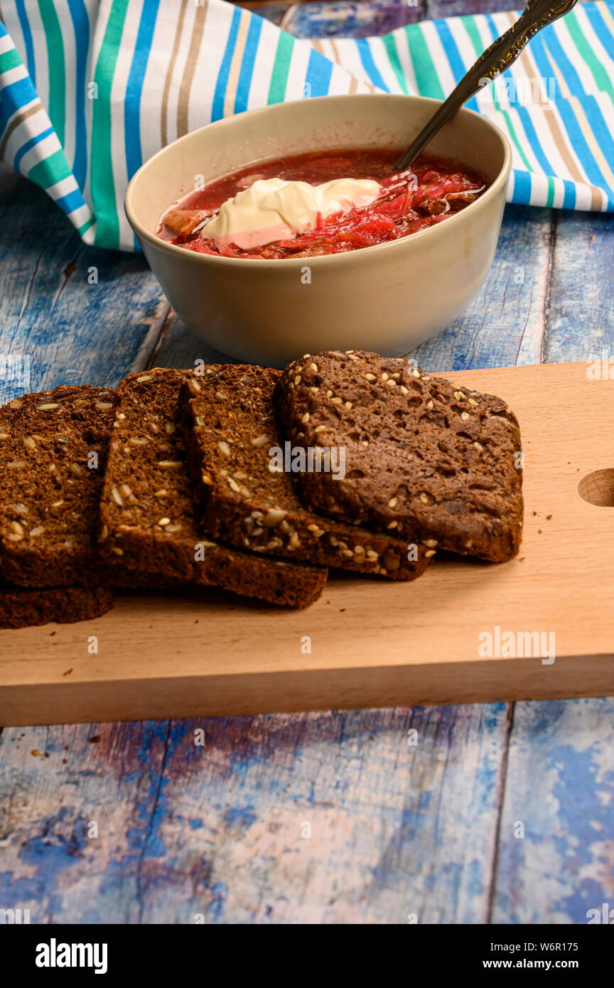 The soup in the plate on the table. Sliced grain bread. Lunch in rustic