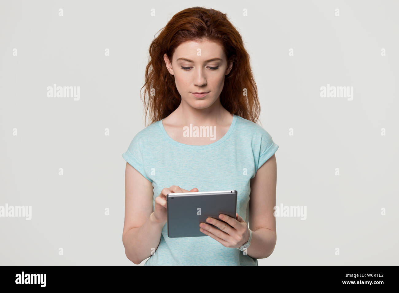 Serious red haired woman using tablet computer studio shot Stock Photo ...