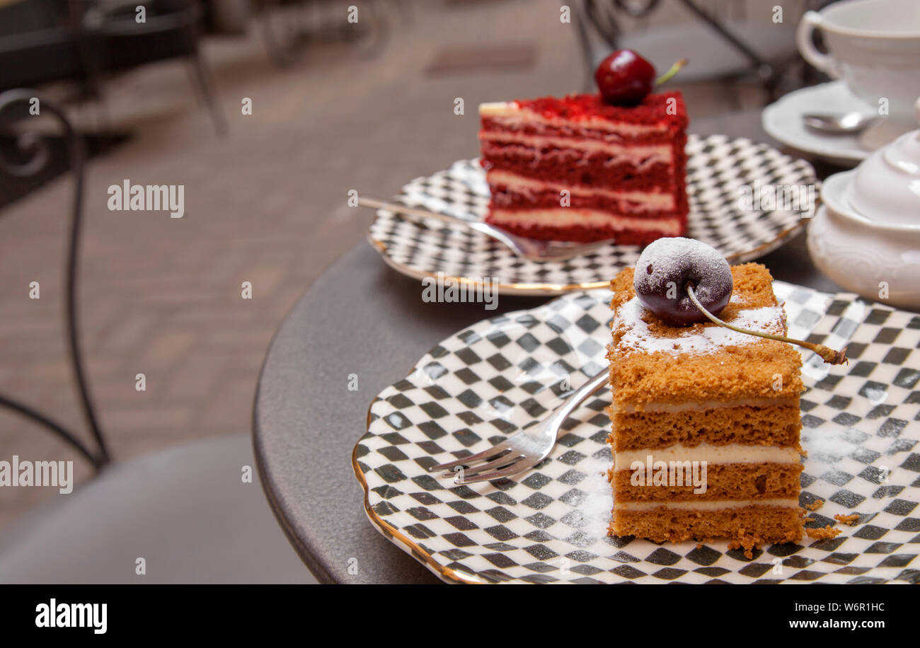 and a cherry on the top - two pieces of different cakes set on a table in a patio cafe Stock Photo