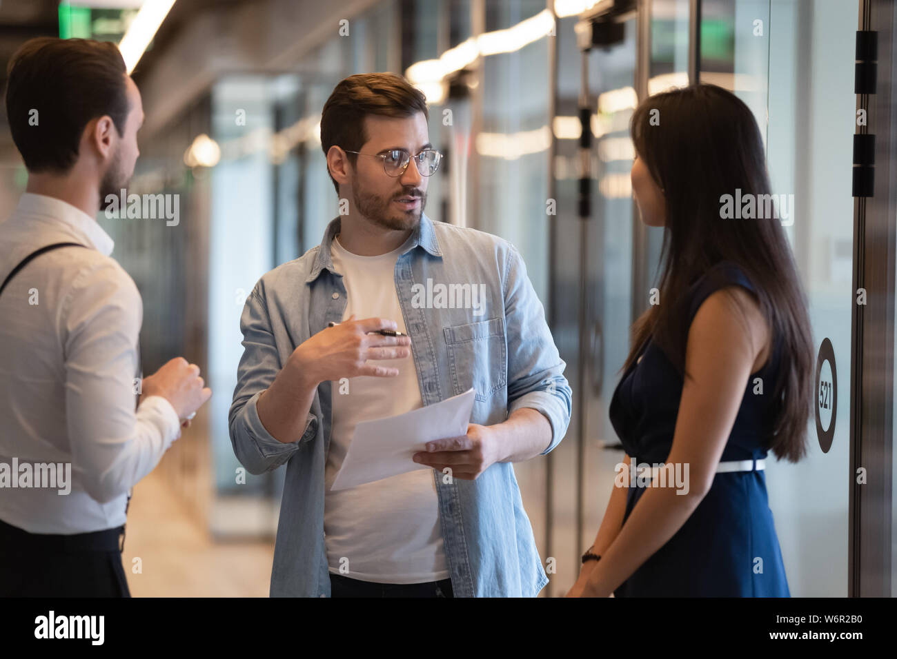 Serious male business leader instructing diverse employees standing in office Stock Photo
