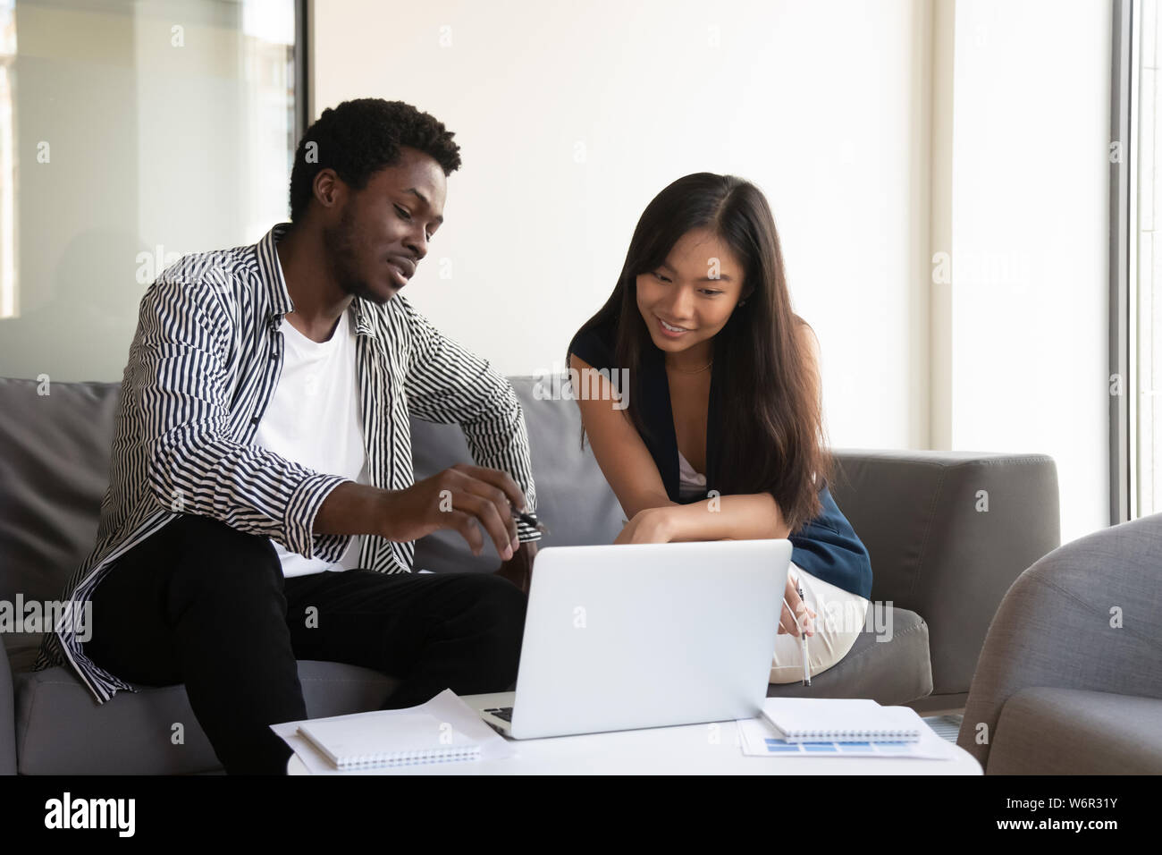 Male black professional mentor help asian intern showing online project Stock Photo
