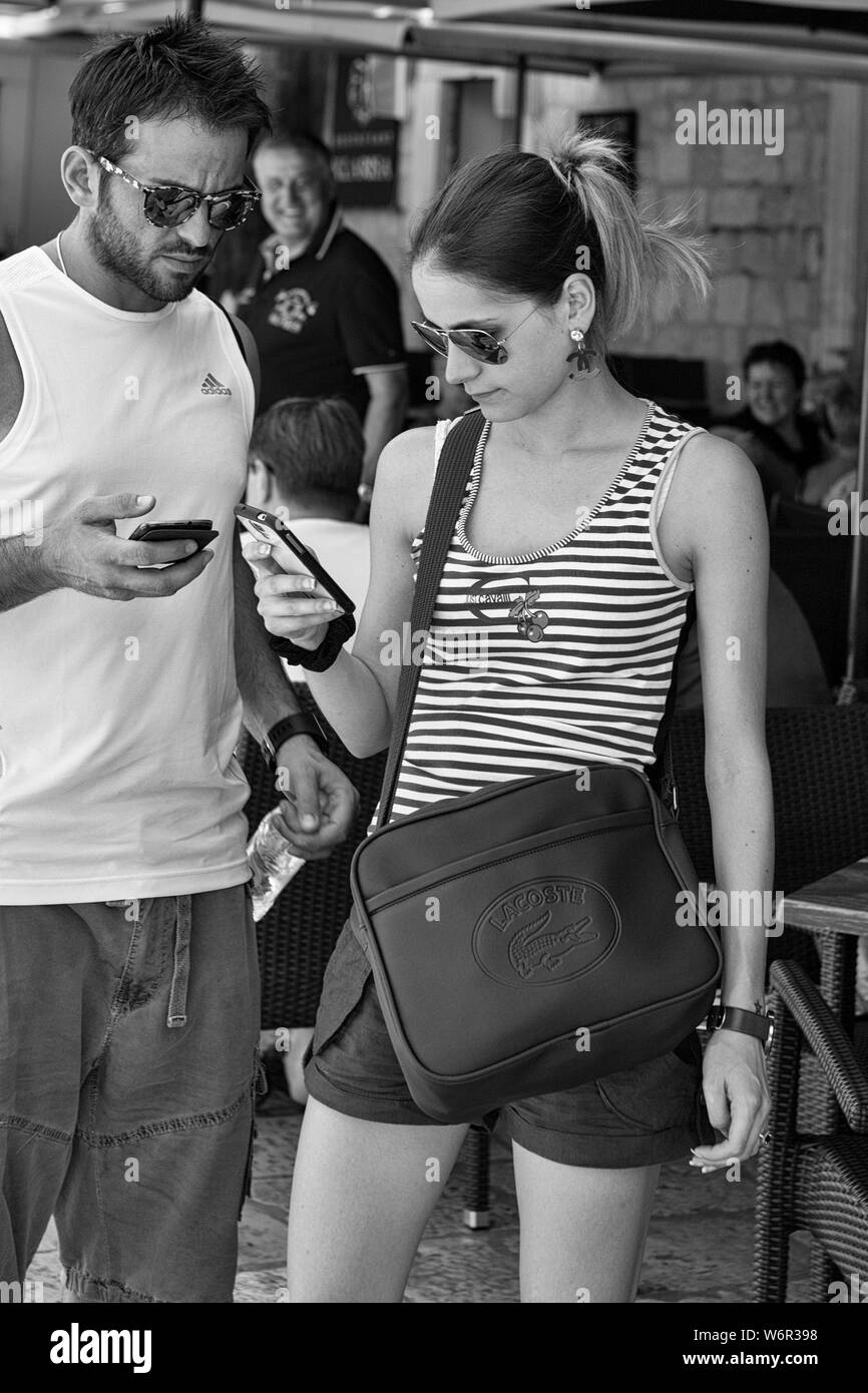 A couple busy with their mobile 'phones, Poljana Paska Miličevića, Dubrovnik, Croatia.  Black and white version Stock Photo