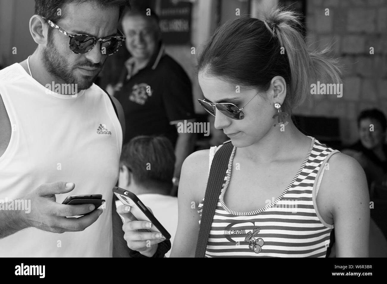 A couple busy with their mobile 'phones, Poljana Paska Miličevića, Dubrovnik, Croatia.  Black and white version Stock Photo