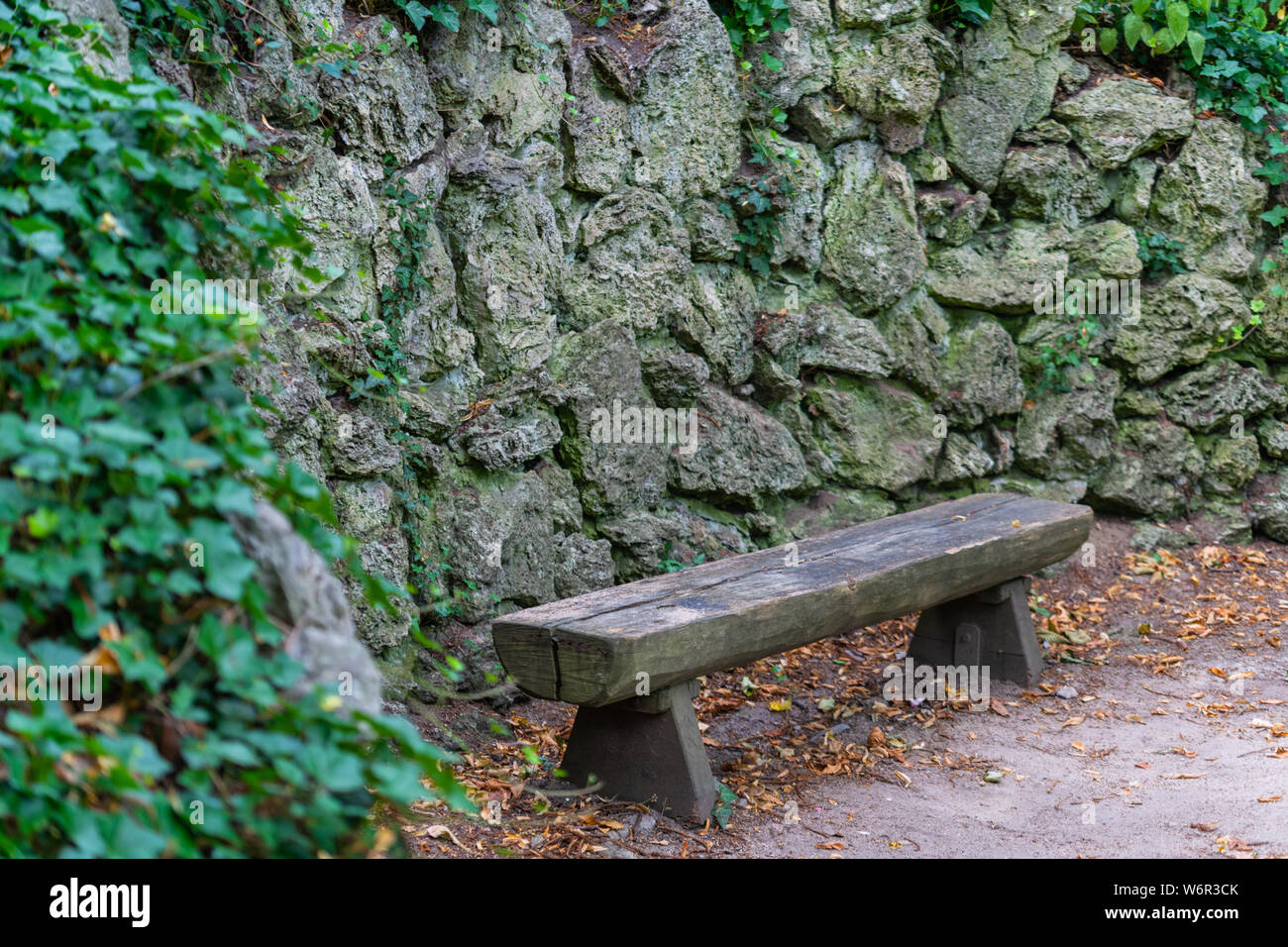 Wooden bench in front of a stone wall Stock Photo - Alamy
