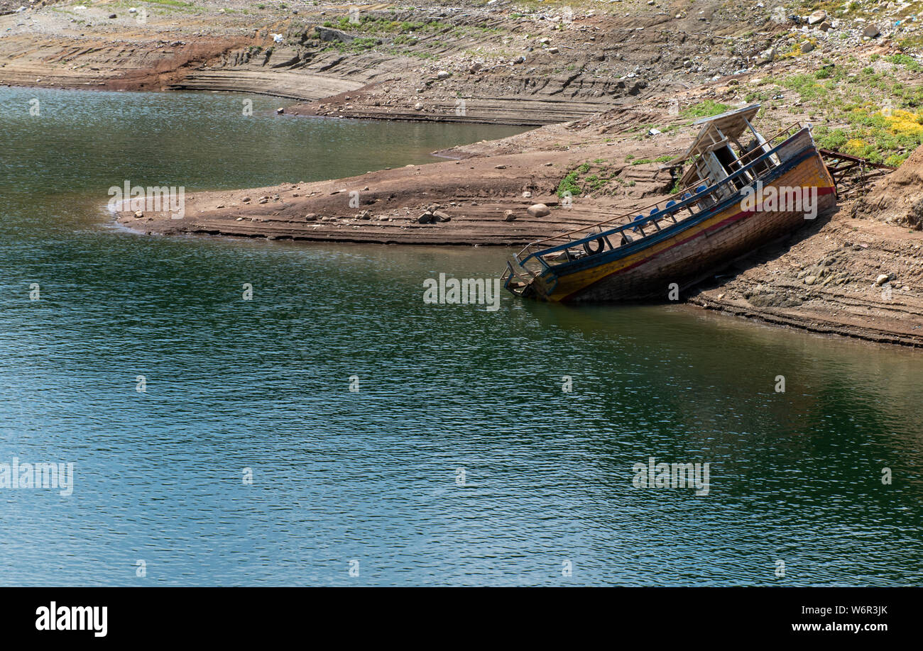 A shipwreck of a fishing boat on the bank of a river Stock Photo