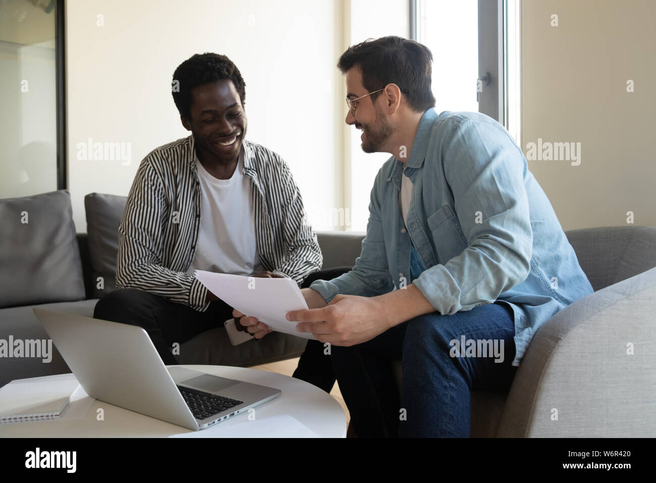 Happy caucasian manager holding papers consulting black client teaching intern Stock Photo