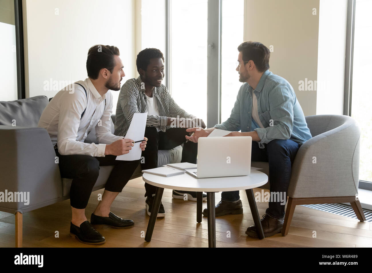Diverse male workers team listen to manager mentor discussing paperwork Stock Photo