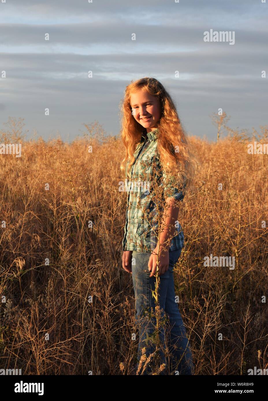 Girl with gold hair in field during sunset Stock Photo