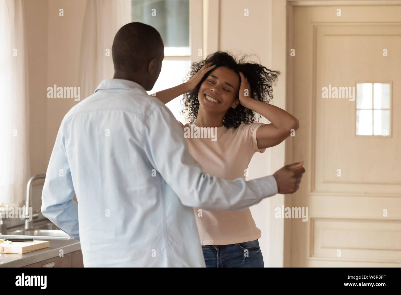 Cheerful active african couple dancing in kitchen Stock Photo
