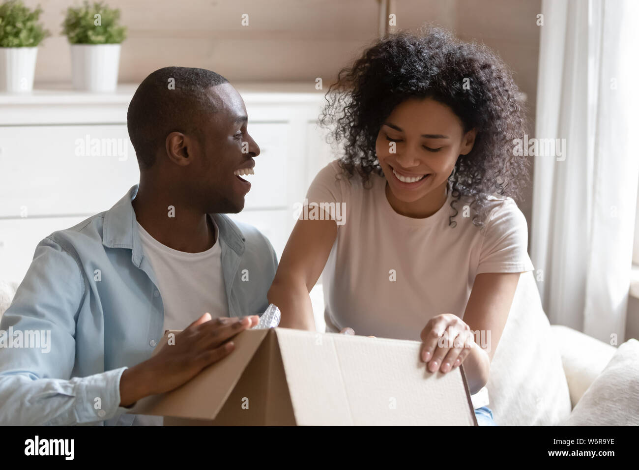 African couple unpack carton box sitting on sofa feels happy Stock Photo