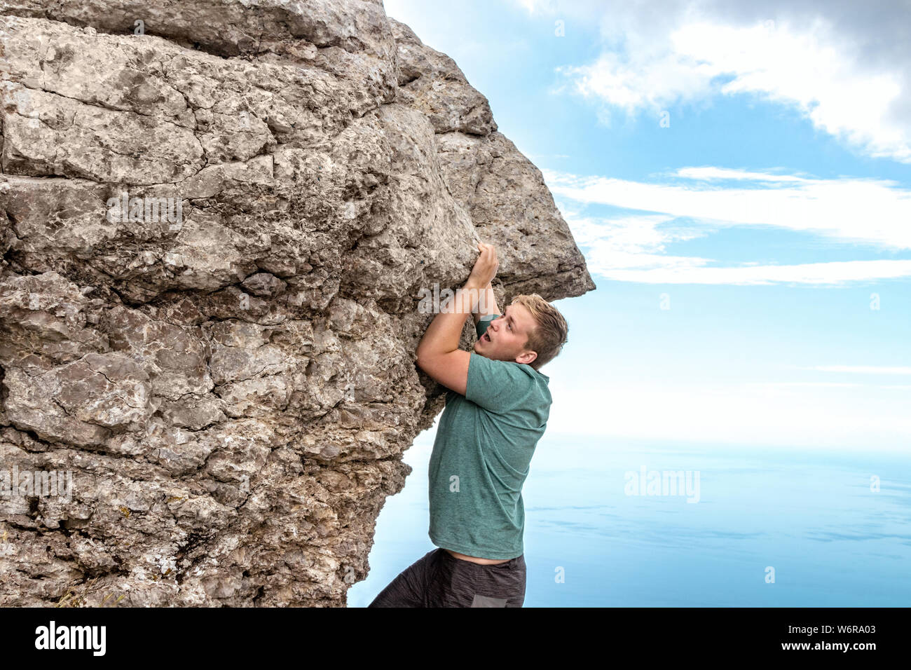 Young man climbing, hanging on edge Stock Photo - Alamy