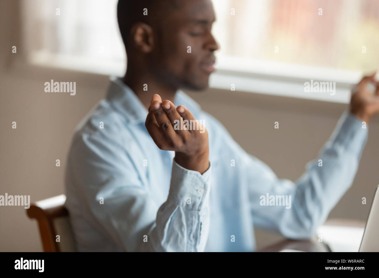 Serene african guy sitting indoors relaxing meditating Stock Photo