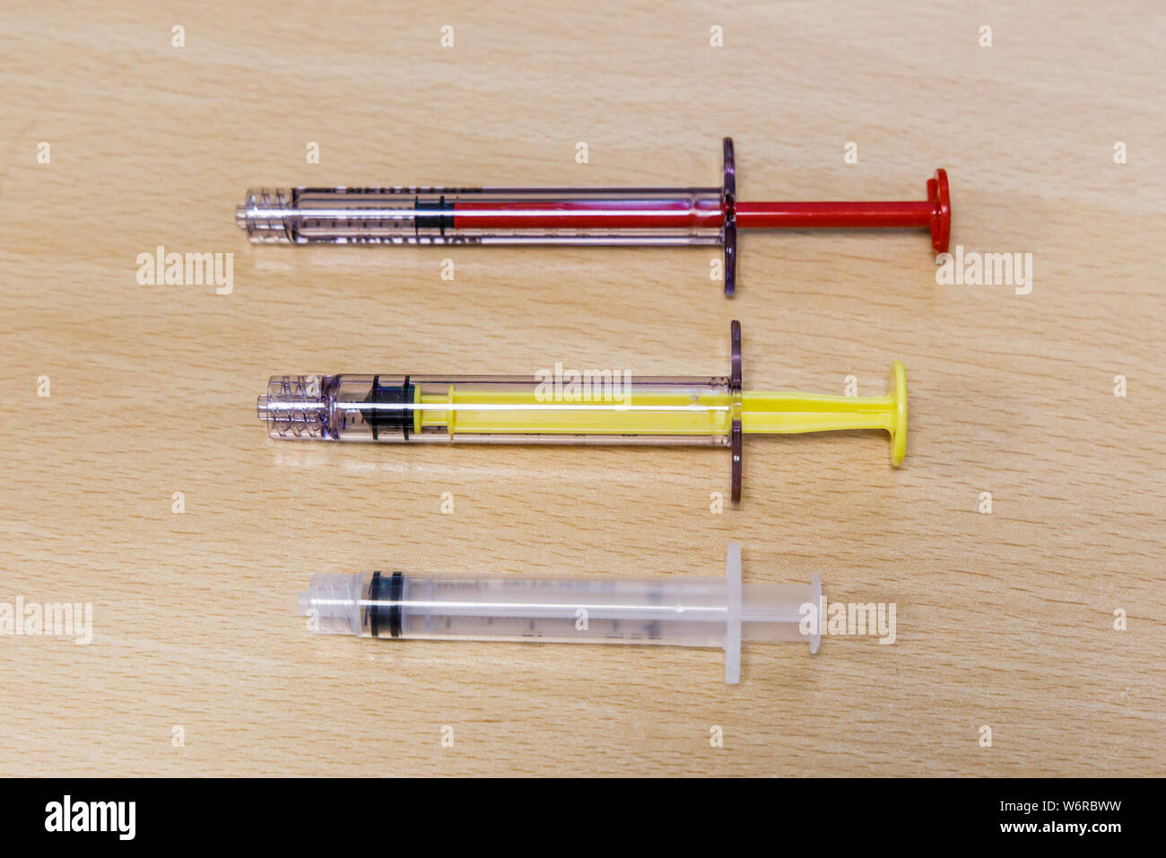 Three small medical syringes of different size and colors Stock Photo Alamy