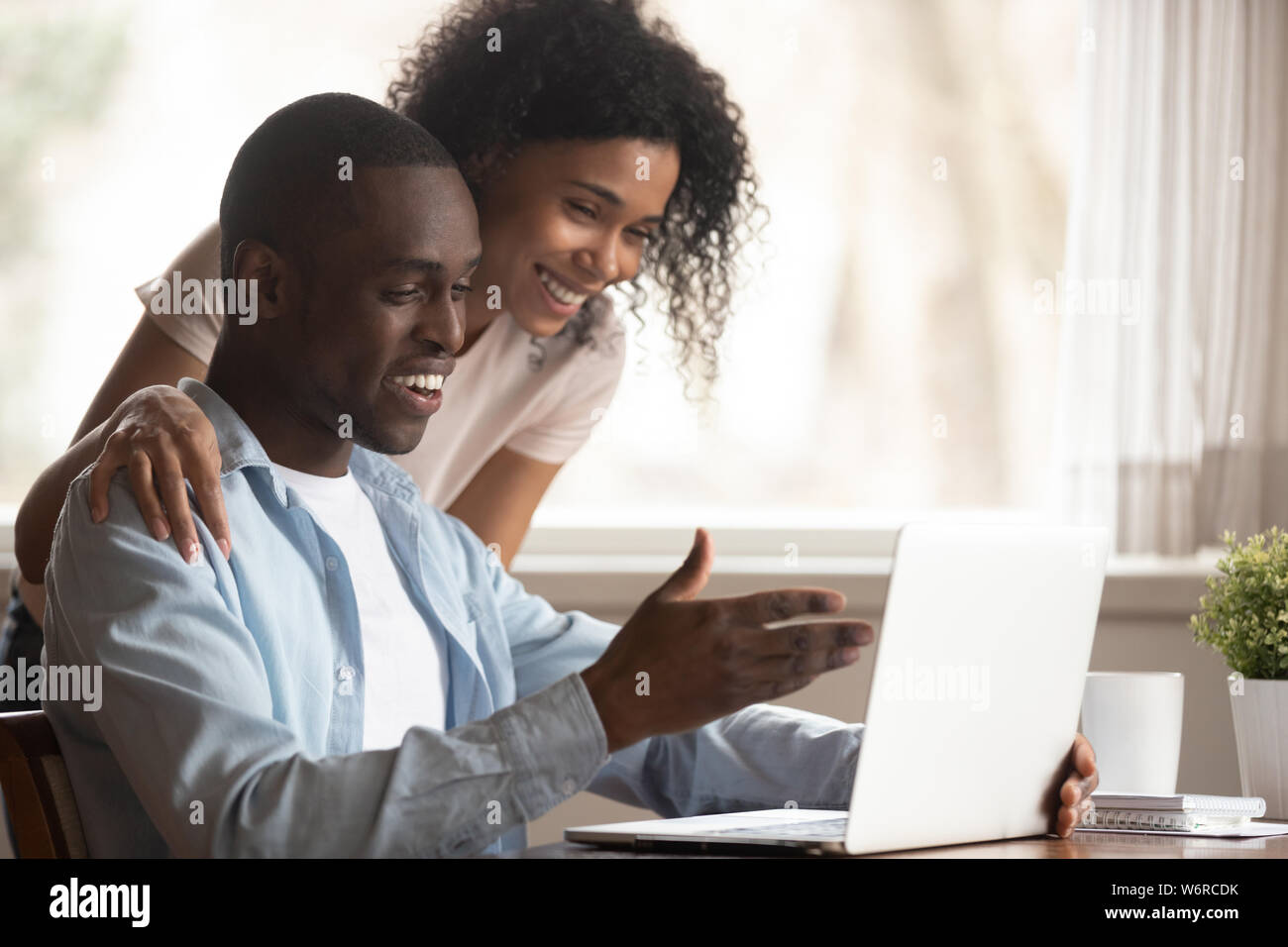 African spouses look at computer screen having fun at home Stock Photo