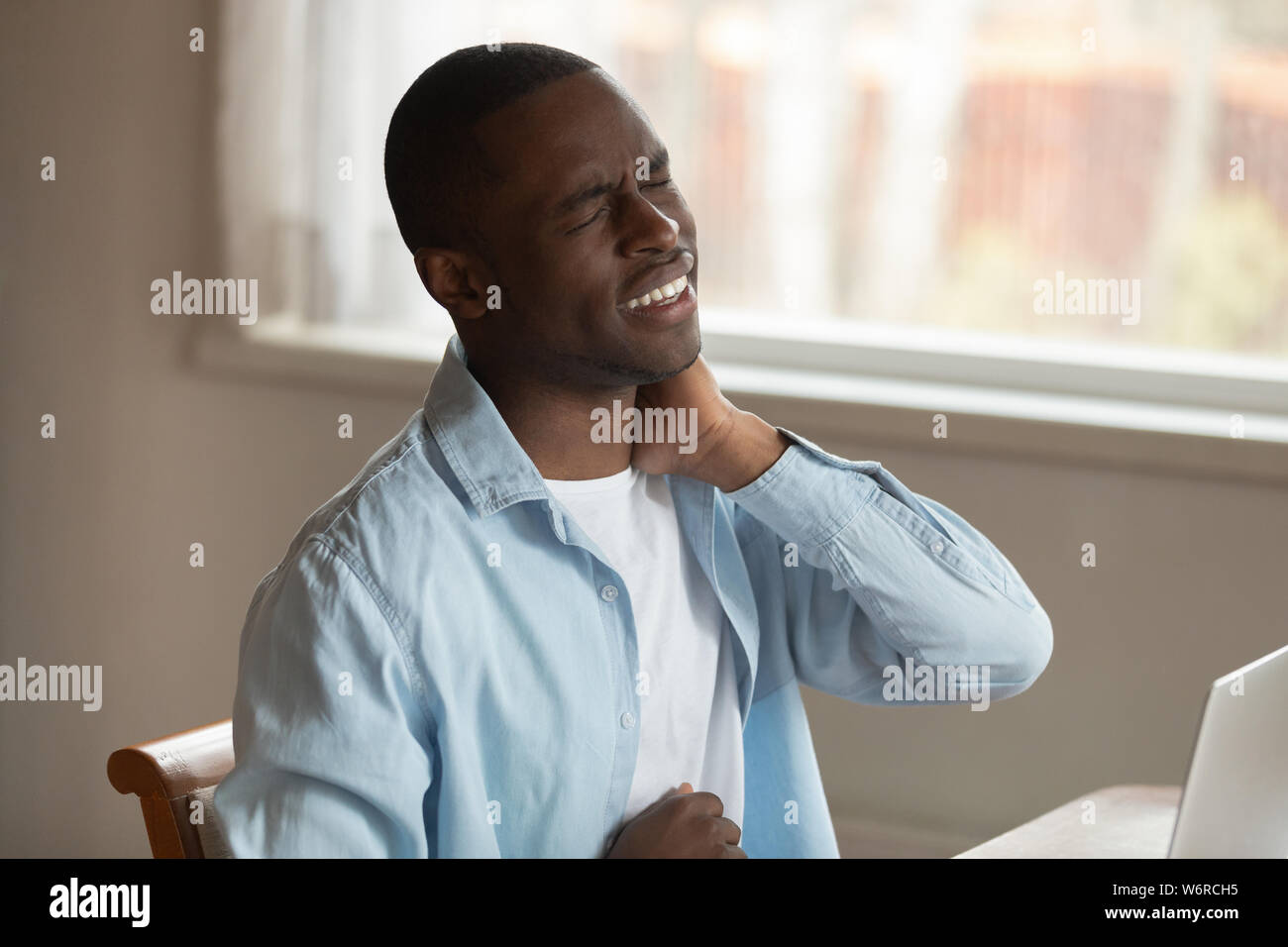 African man frowning massaging pinched nerve feels pain in neck Stock Photo