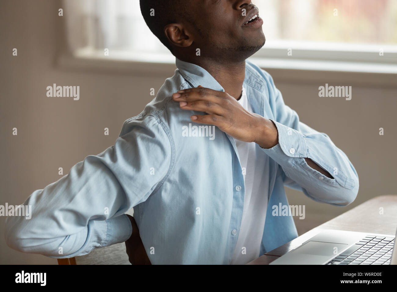 Cropped image african guy touch shoulder suffers from painful sensations Stock Photo