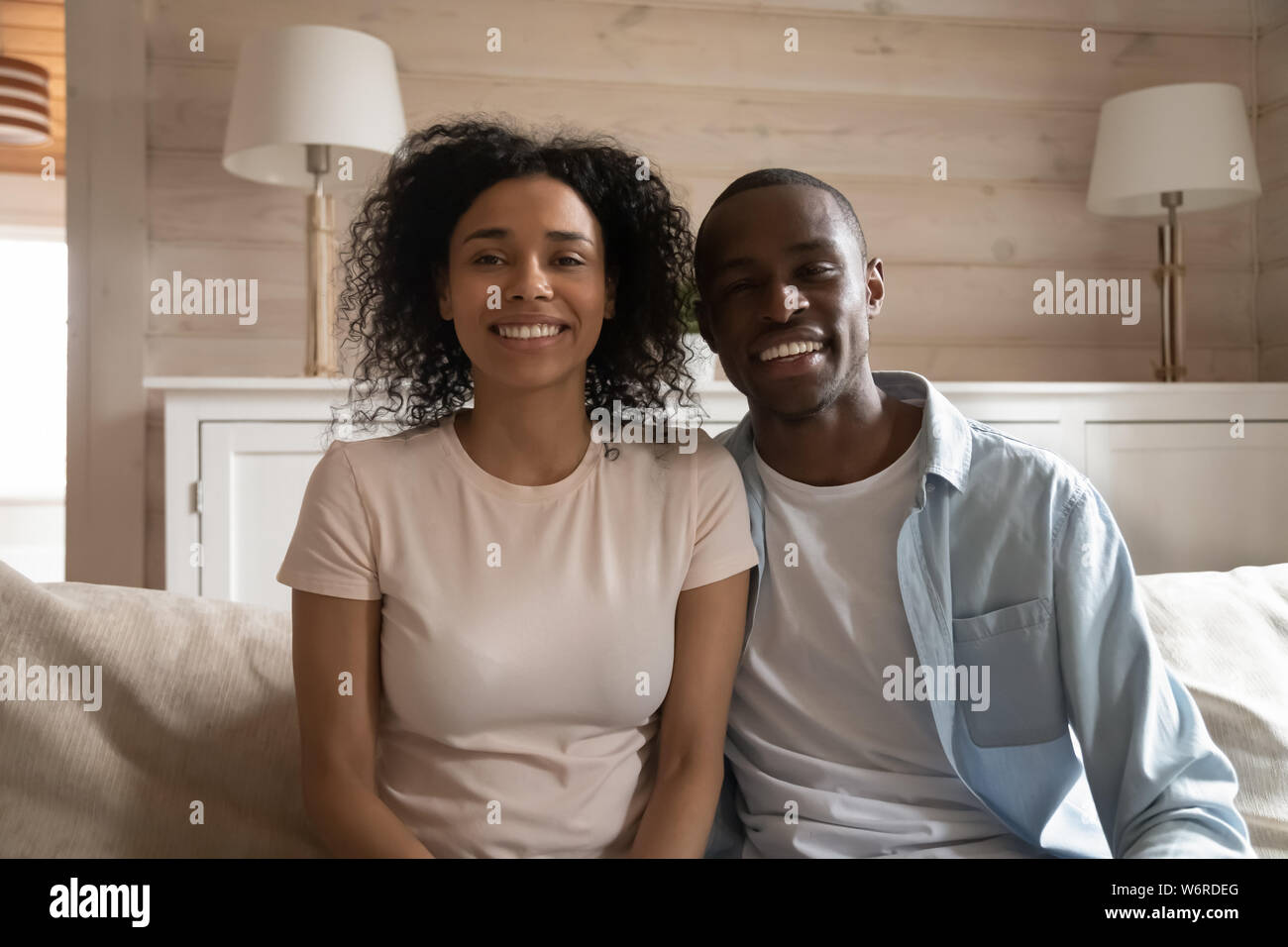 Smiling african couple sitting on couch making video call Stock Photo ...