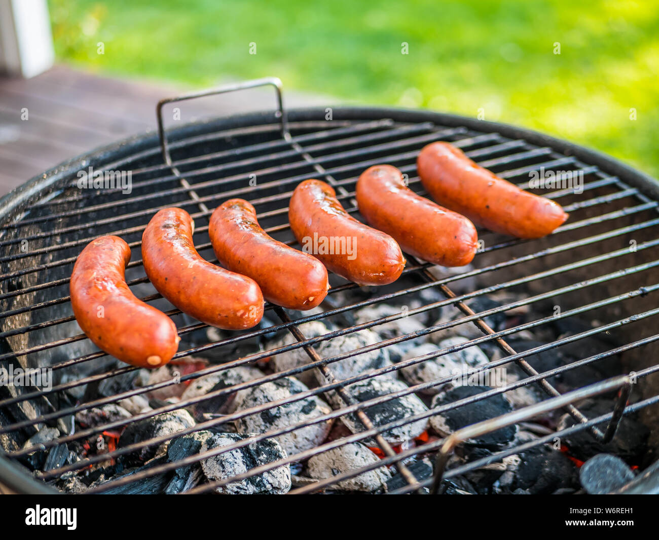 Grill Sausage on a hot col or briquettes at home or in the back yard. Stock Photo