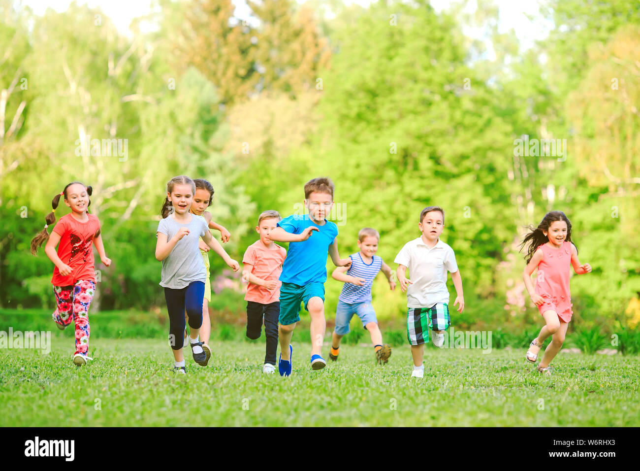 Many different kids, boys and girls running in the park on sunny summer day in casual clothes Stock Photo