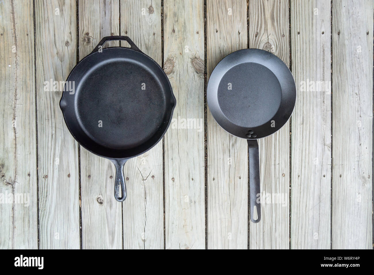 Traditional cast iron vs carbon steel versus teflon cooking options - blank empty room for text or copy space. Two cookware pieces - kitchen stove to Stock Photo
