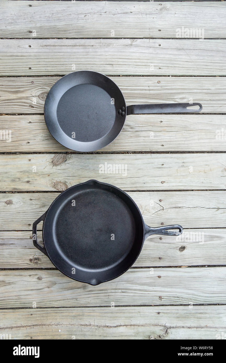 Traditional cast iron vs carbon steel versus teflon cooking options - blank empty room for text or copy space. Two cookware pieces - kitchen stove to Stock Photo