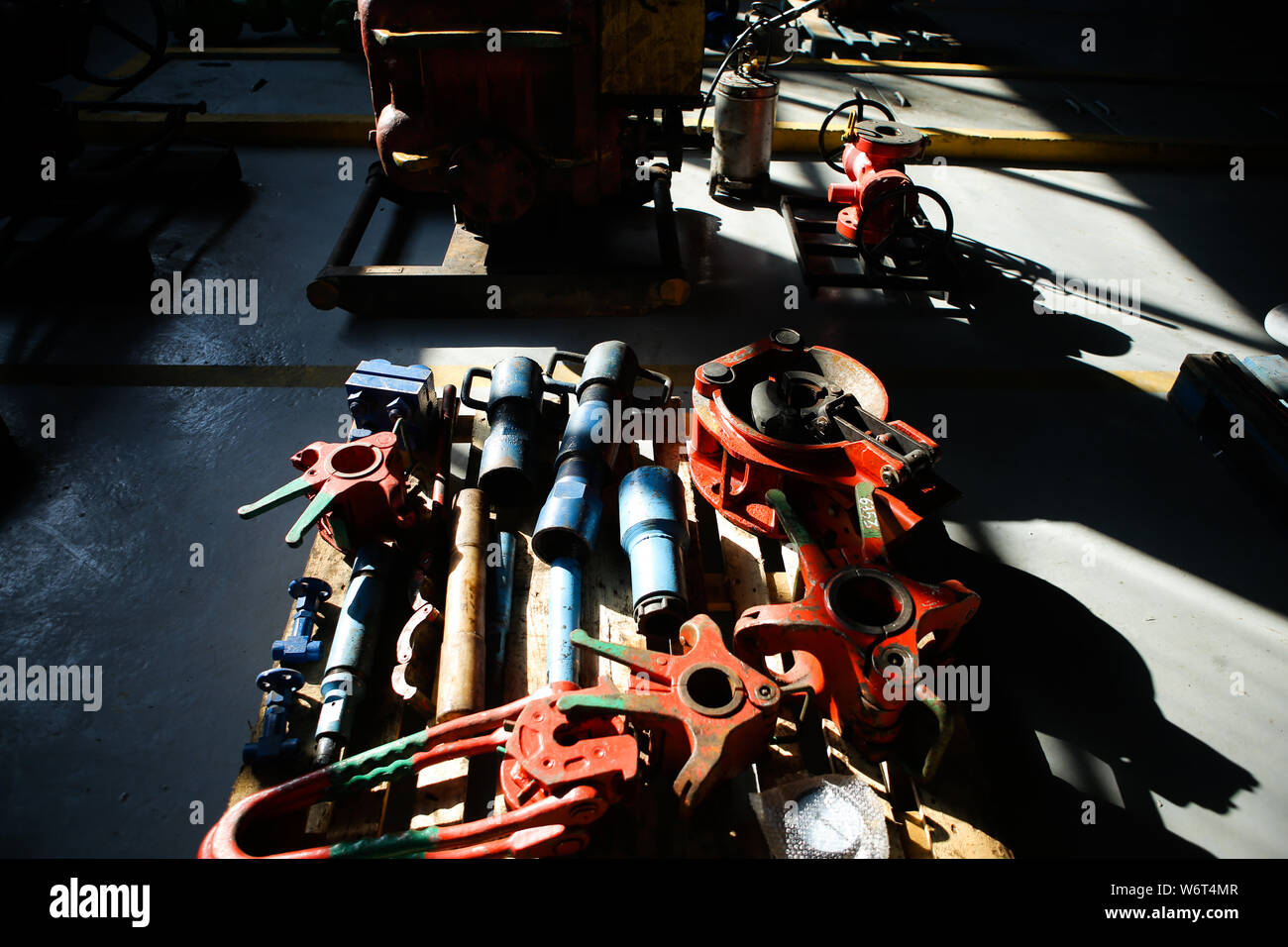 Shallow depth of field image with iron industrial equipment used in the oil and gas drilling industry laid on the ground of a workshop Stock Photo